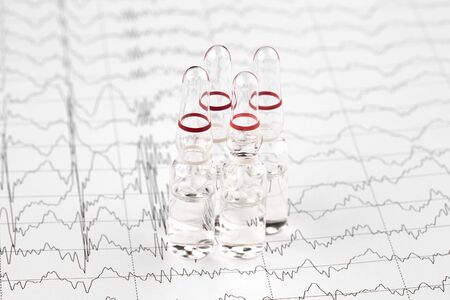 Close-up photo of ampoules with medicine on EKG graph.