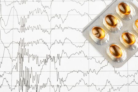 Close-up photo of blister with yellow pills on EKG graph.