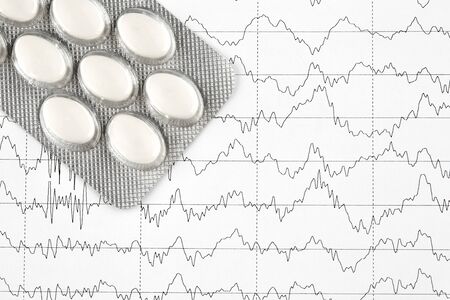 Close-up photo of blister with white pills on EKG graph.の写真素材