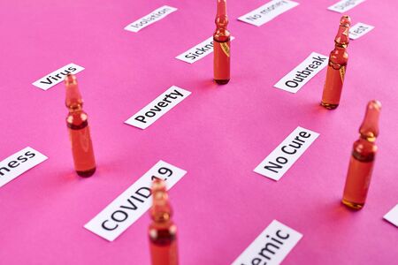 Ampoules with medicine and coronavirus, pandemic headline clipping words on pink background.