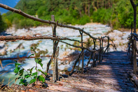 cozy wooden bridge crossing over a stormy mountain riverの写真素材