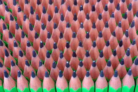 Macro image of graphite tip of a sharp ordinary wooden pencil as drawing and drafting tool, standing among other pencils, symbolizing individuality approach and concept as standing out from the crowdの写真素材