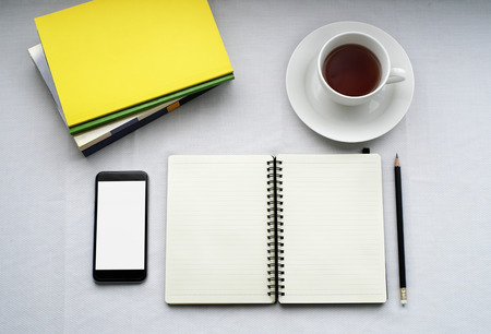 Tea in white cup with Journal book and smartphoneの写真素材