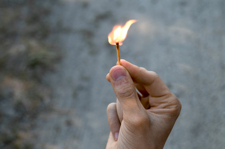 Right hand of adult man. The flame from the match pointing to the up and right.の写真素材