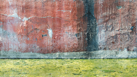 Grunge concrete wall and green polluted water at ground.
