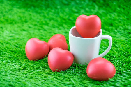 Red heart in coffee cup on grass, Love concept.の写真素材