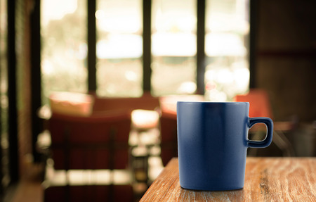 Dark Blue Coffee cup on wood table in blur cafe background.の写真素材