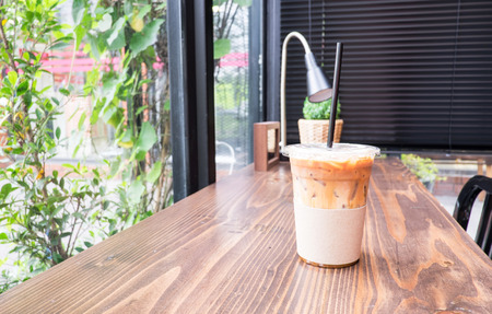 Ice coffee on wood table beside window in coffee shop at garden.の写真素材