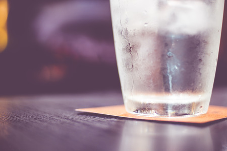 Vintage filter : Cold glass of water on wooden table at restaurant.の写真素材