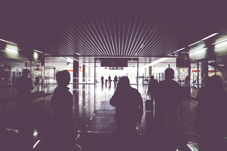 Vintage filter : silhouette of passenger walking through train gate with light at the end of gate.の写真素材