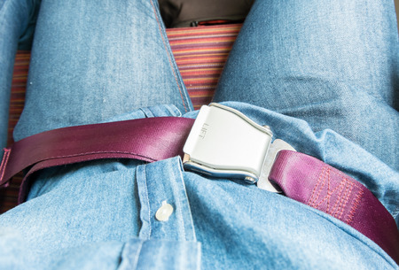 Hand fasten seat belt at seat on airplane before take off.の写真素材
