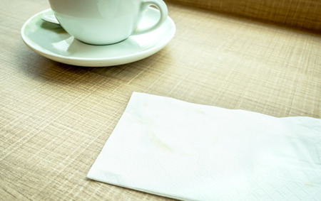 Vintage filter : Tissue paper with coffee stain and coffee cup on wood tableの写真素材
