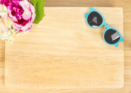 Top view of Blank wooden plate with flower and sunglasses on table top,Mock up for adding your designの写真素材