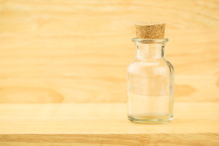Glass bottle with cork on wood table and blur wooden wall, Copy space for adding your content.の写真素材