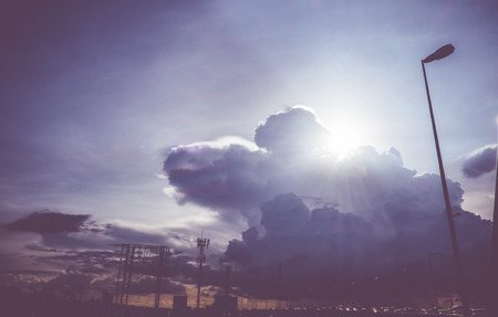 Vintage filter, Looking up at Sun behind cloud on road.