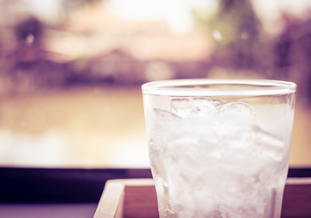 Vintage filter : Cold glass of water on wooden table at restaurant.の写真素材