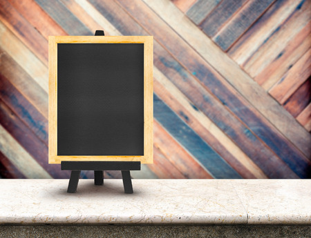 Blackboard menu with easel on marble table with blur diagonal wood wall at  restaurant background, Copy space for adding your content.の写真素材