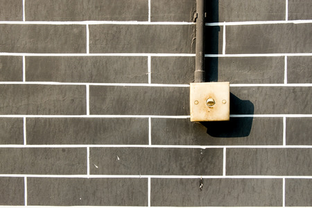 Old light switch on grey brick wall, outddor