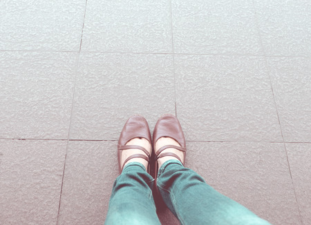 Vintage filter : aerial view of woman shoe wear blue jean stand on pavement