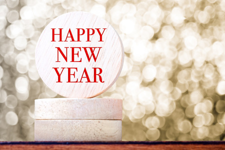 happy new year on round wood tag with golden bokeh background,holiday concept.の写真素材