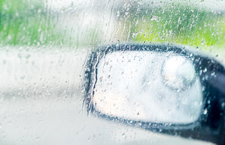 See through car window to side rear-view mirror in raining day.の写真素材
