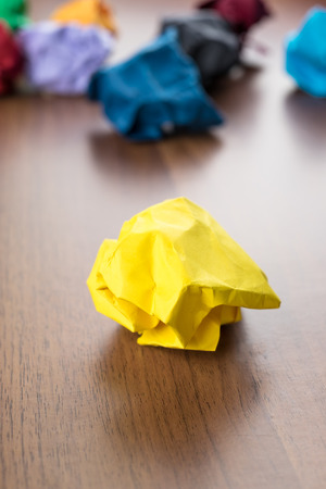 yellow crumpled paper ball on dark brown wood table with group of colorful crumpled paper ball at background,Creative idea concept.の写真素材