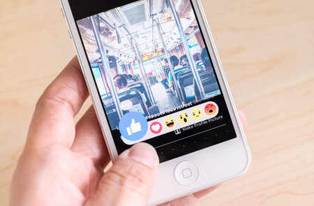 Bangkok, Thailand - February 26, 2016: Hand holding iPhone with New facebook like button (6 emoji)...