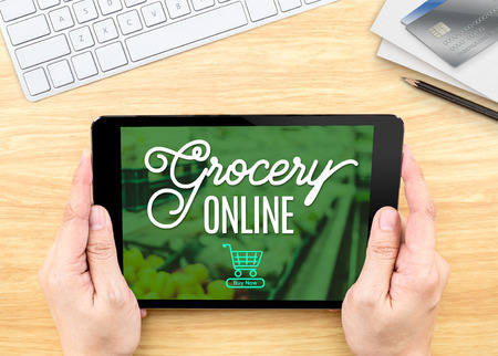 Hand holding tablet with grocery online word on wood table ,Shopping online conceptの写真素材