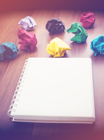open blank ring binder white book and pencil with group of colorful crumpled paper ball on dark brown table top, Business Brainstorming concept,mock up for adding your text.の写真素材