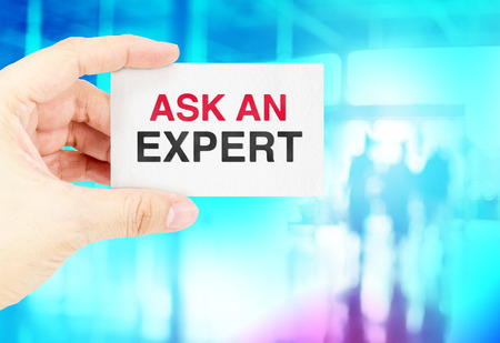 Hand holding Business card with Ask an expert with blur blue bokeh backgroundの写真素材