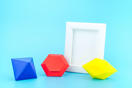 White photo frame(made from paper) and colourful paper jewels on light blue background,Modern home decoration,Leave space to adding your photo.の写真素材