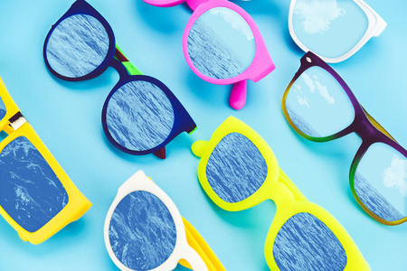Set of sunglasses lay on blue ground with sea and sky reflection on glass,Summer ,concept,vintage filter.の写真素材