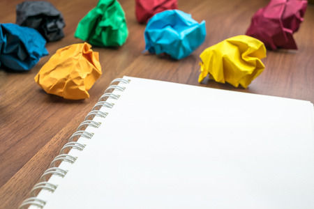 open blank ring binder white book  with group of colorful crumpled paper ball on dark brown table top, Business Brainstorming concept,mock up for adding your text.の写真素材
