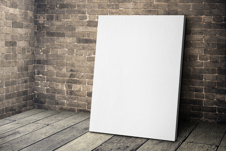 Blank white canvas frame leaning at grunge brick wall and wood floor, Mock up template for adding your designの写真素材