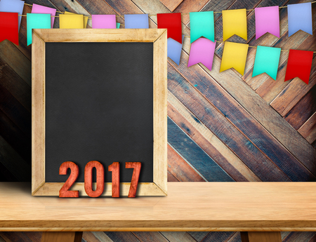 Happy new year on blackboard with gift and colorful flag banner on wood table at diagonal wood wall,Leave space for display or montage of your design.の写真素材