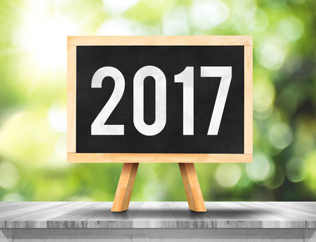 2017 new year on blackboard on plank white wood with green abstract blur tree background,Ecology Business concept.の写真素材