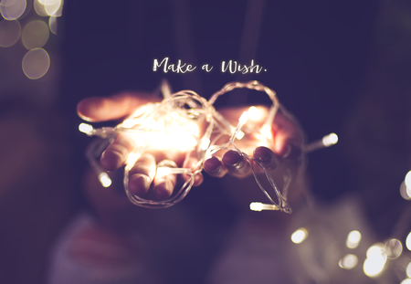 Make a wish word over hand with light bokeh in vintage filter,Holiday quote,christmas season.の写真素材