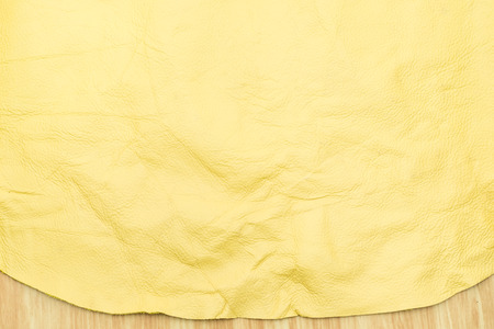 Close up at bright yellow color leather texture on wood table.の写真素材