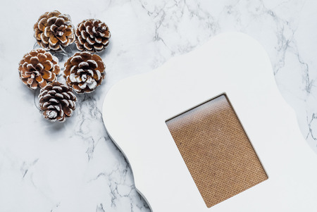 vintage white photo frame with pine cones on white marble table top,Holiday decoration card.の写真素材