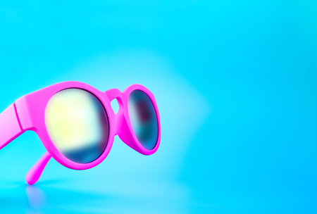 shocking pink color sunglasses at light blue studio background,Summer Holiday concept.Leave space for adding text.の写真素材