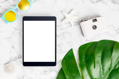 Blank screen tablet computer on marble table top view with summer beach accessories and monstera leaves ,Summer vacation concept,Mock up template for adding your design or text.の写真素材