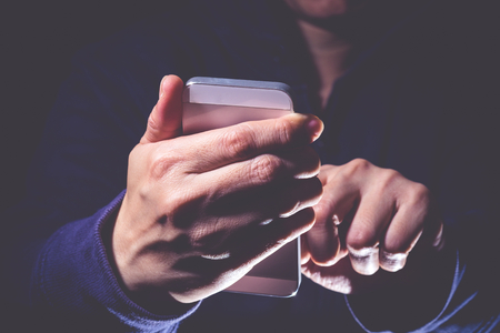 Hooded cyber crime hacker using mobile phone internet hacking in to cyberspace,online personal data security conceptの写真素材