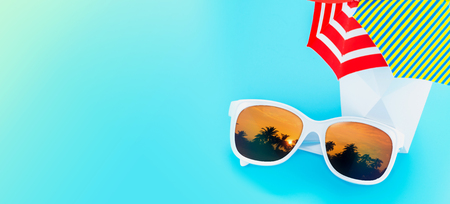 White Sunglasses reflection sunset at palm tree landscape scene with mini parasol in cocktail white glass in light blue studio ,Summer Time banner,Leave space for adding your content or design.の写真素材