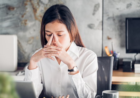 Frustrated Asian businesswoman cover her face with two hand and feel upset from work in front of laptop computer on desk at office,Stress office lifestyle conceptの写真素材