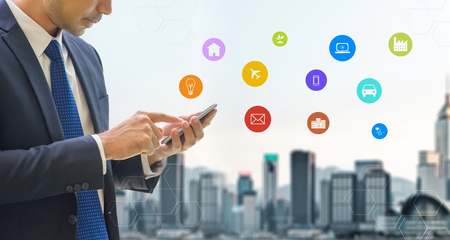 Business man wear suit using mobile phone control Internet of things features diagram icon with blur...