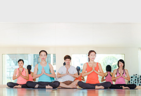 Yoga class in studio room,Group of people doing namaste pose with calm relax emotion,Meditation pose,Wellness and Healthy Lifestyle.の写真素材