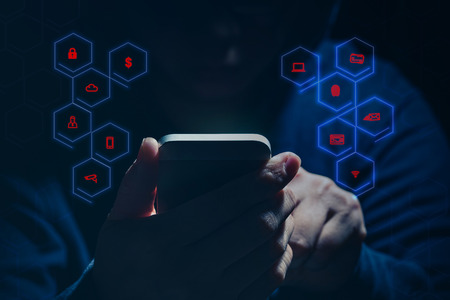 Hooded cyber crime hacker using mobile phone internet hacking in to cyberspace,online personal data security concept.の写真素材