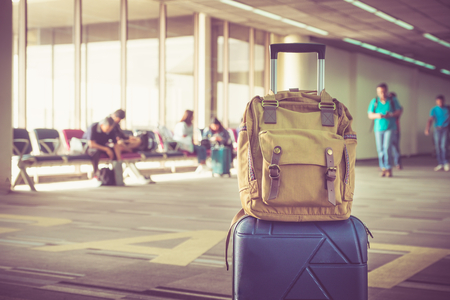 Suitcases and backpack in airport departure terminal with traveler people walking in background,Holiday vacation concept, Business tripの写真素材