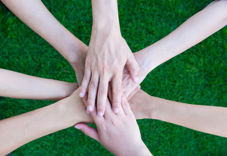 Close up asian business people hands together over green grass out of office,Teamwork concept.