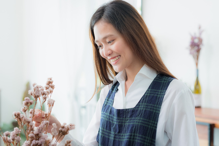 Asian female florist concentrated on decorate flower on vase in shop with smiling face.の写真素材